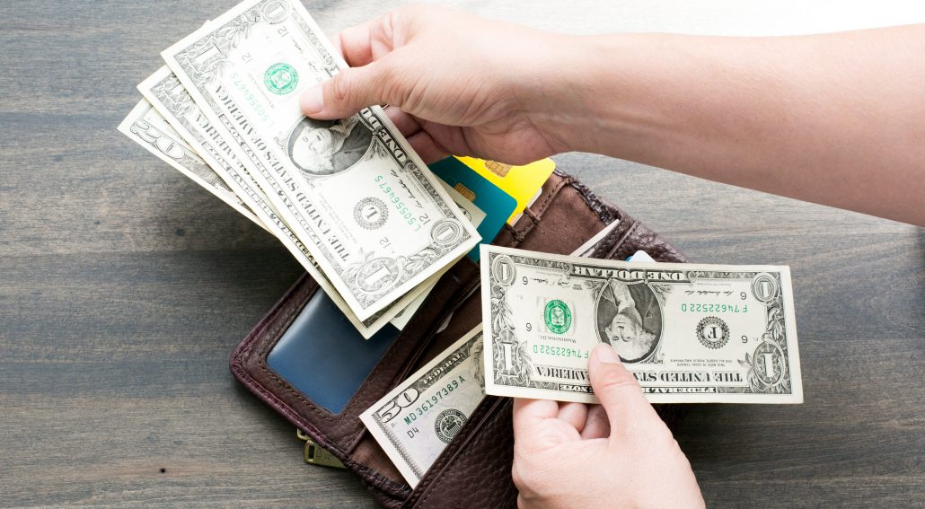 wallet-and-money_4460x4460 A wallet with dollar bills being held near it